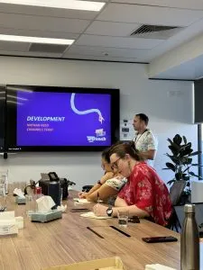 Nathan stands in front of a screen with a purple slide which reads Development Nathan Reid, Channels Team.