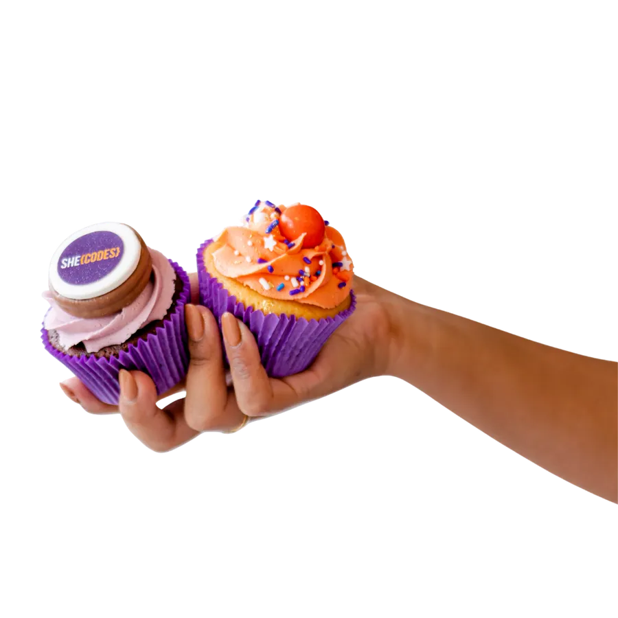 A hand holding two She Codes Australia branded cupcakes