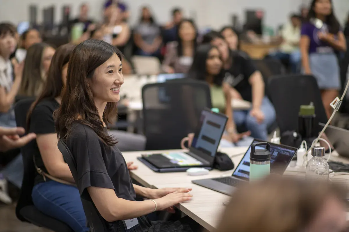 An attendee smiling while working at a laptop during a She Codes workshop